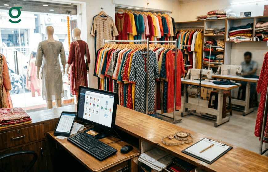 Tailor shop workspace with computer and clothing racks managed through tailor app